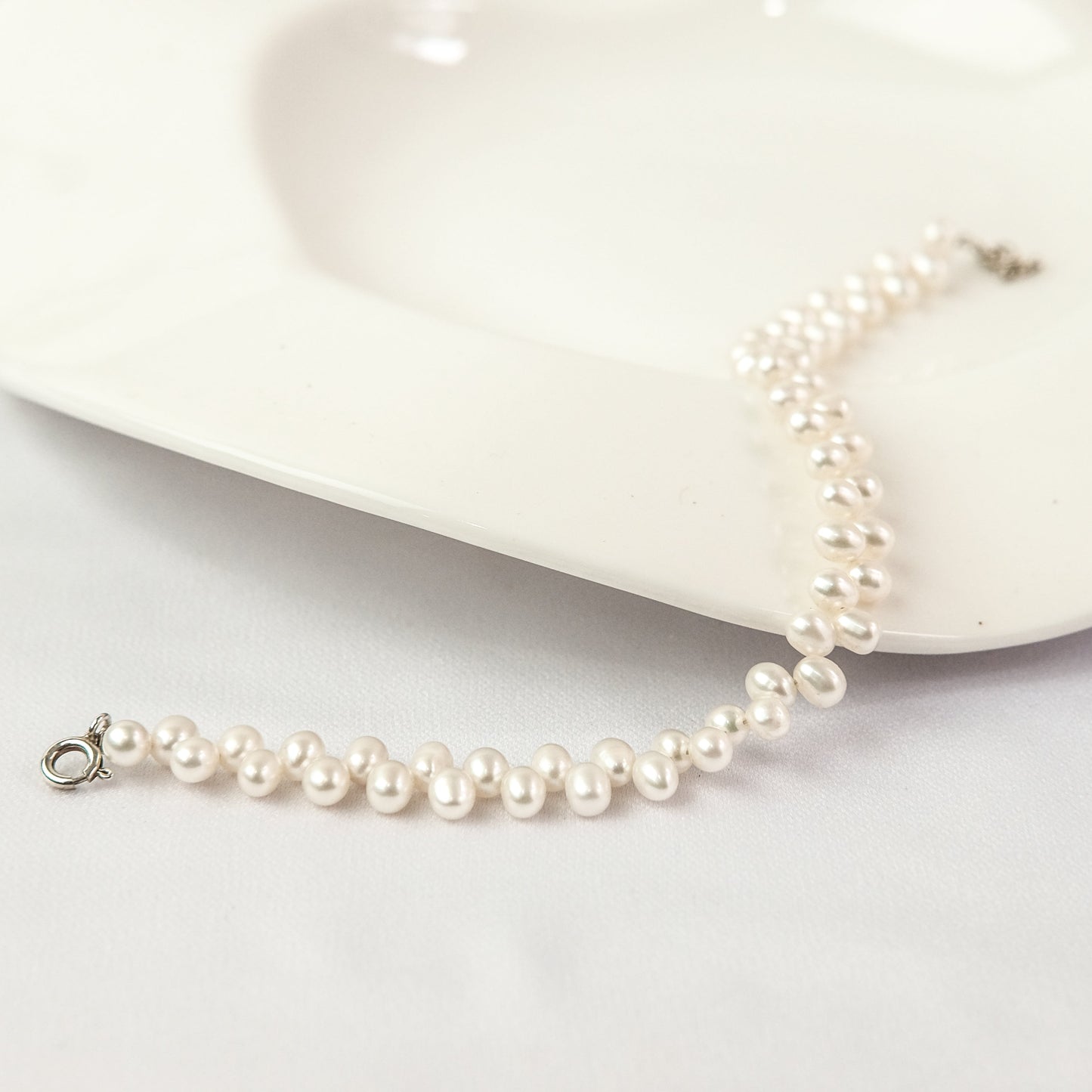 Verso Pearl bracelet on a white dish with a white background